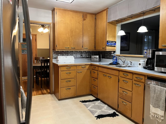 kitchen featuring appliances with stainless steel finishes, sink, backsplash, ceiling fan, and decorative light fixtures