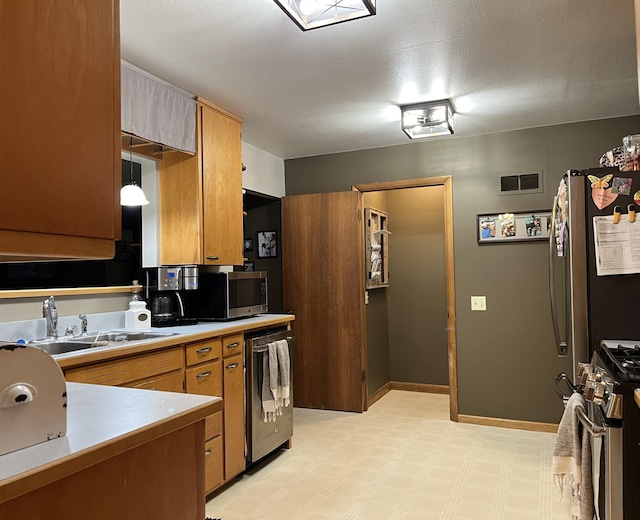 kitchen with stainless steel appliances, a textured ceiling, sink, and hanging light fixtures