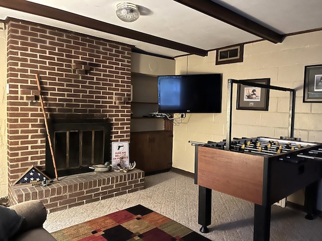 recreation room featuring carpet floors, beamed ceiling, and a fireplace