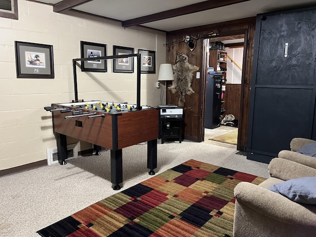 recreation room with beamed ceiling and light colored carpet