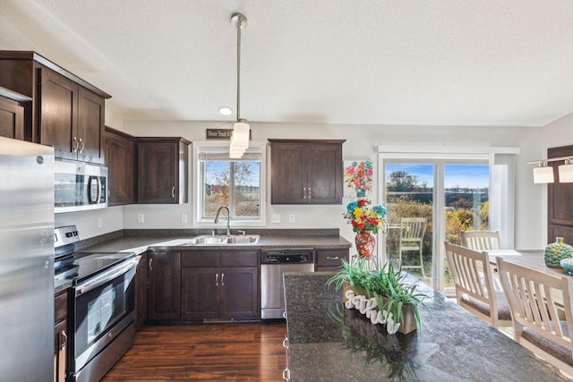 kitchen featuring dark wood-type flooring, hanging light fixtures, sink, appliances with stainless steel finishes, and a textured ceiling