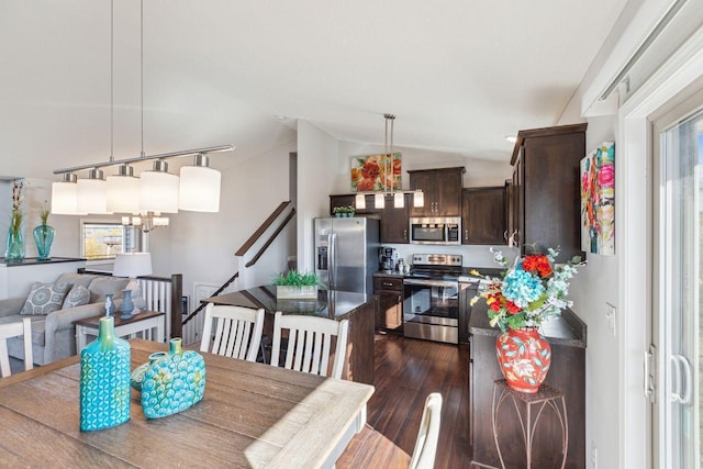 dining area featuring an inviting chandelier, a healthy amount of sunlight, dark wood-type flooring, and vaulted ceiling