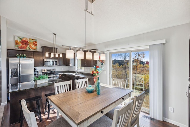 dining room with sink, a textured ceiling, and dark hardwood / wood-style flooring