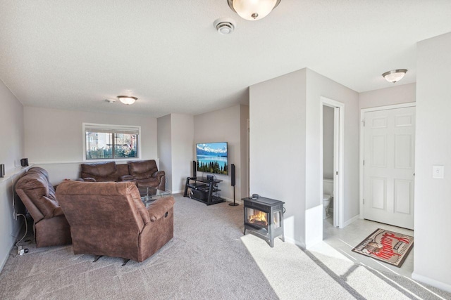 carpeted living room featuring a wood stove and a textured ceiling