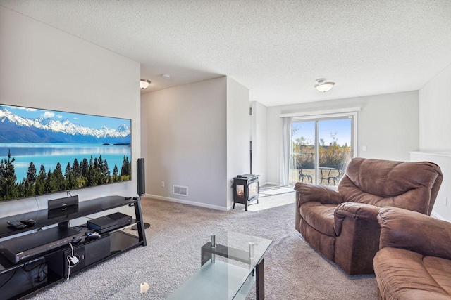 living room featuring a wood stove, a textured ceiling, and light colored carpet