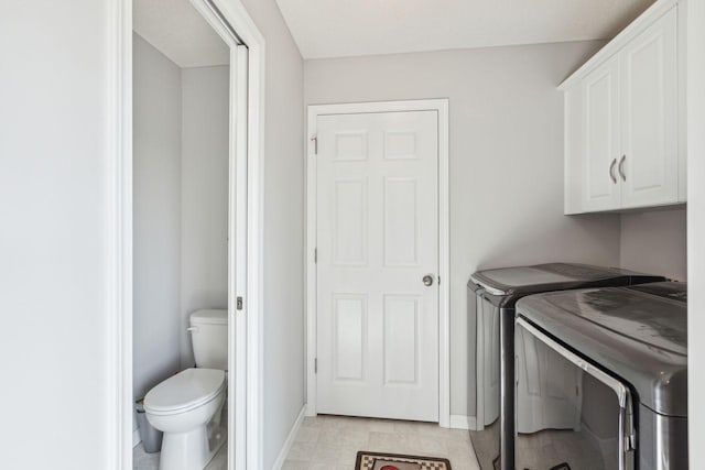 laundry room with light tile patterned floors, cabinets, and washing machine and clothes dryer