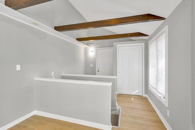 hallway with light hardwood / wood-style floors and lofted ceiling with beams