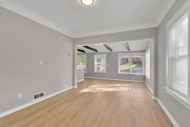 empty room with ceiling fan, lofted ceiling with beams, and light wood-type flooring