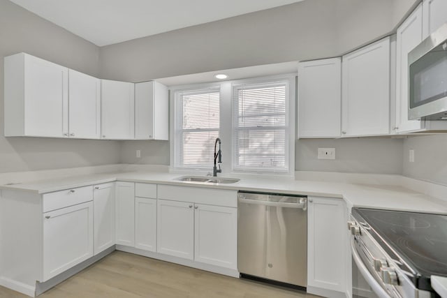 kitchen featuring white cabinets, stainless steel appliances, sink, and light wood-type flooring