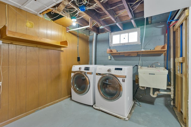 laundry room with wood walls, sink, and separate washer and dryer