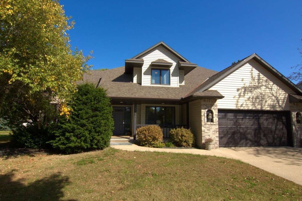 view of front of home featuring covered porch, a garage, and a front lawn