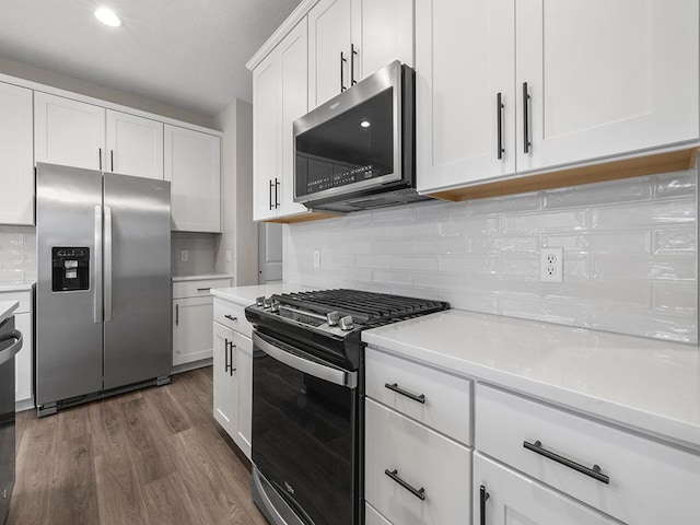 kitchen with white cabinets, dark hardwood / wood-style flooring, stainless steel appliances, and backsplash