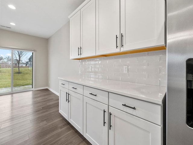 kitchen featuring decorative backsplash, white cabinetry, stainless steel refrigerator, and dark hardwood / wood-style floors