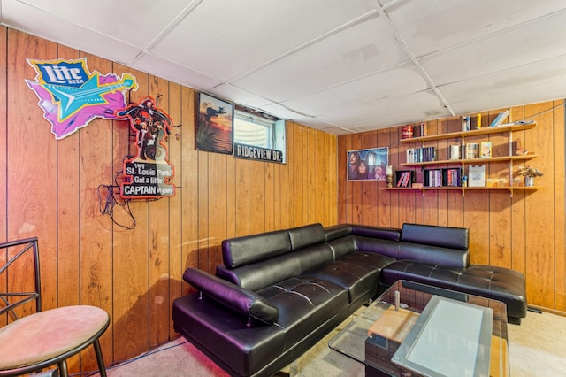 living room with light carpet, a drop ceiling, and wood walls