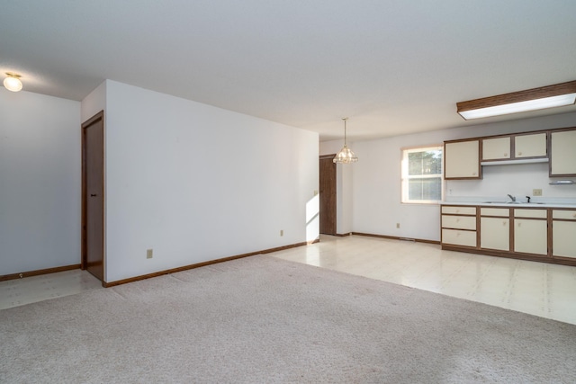 unfurnished living room featuring a chandelier, light colored carpet, and sink