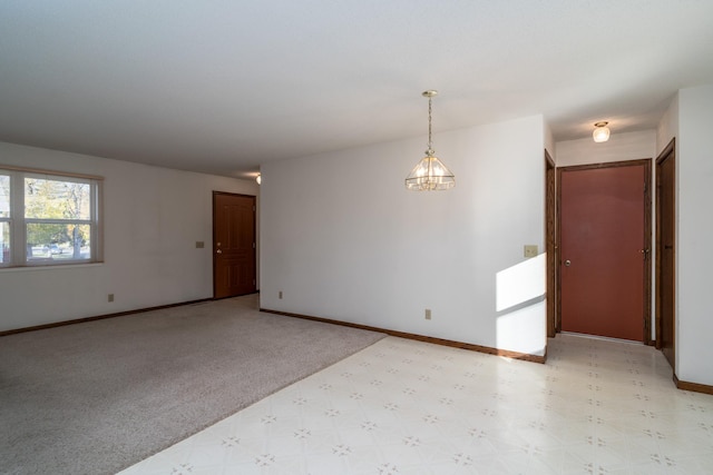 carpeted spare room with a notable chandelier