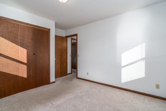 unfurnished bedroom featuring light carpet and a closet