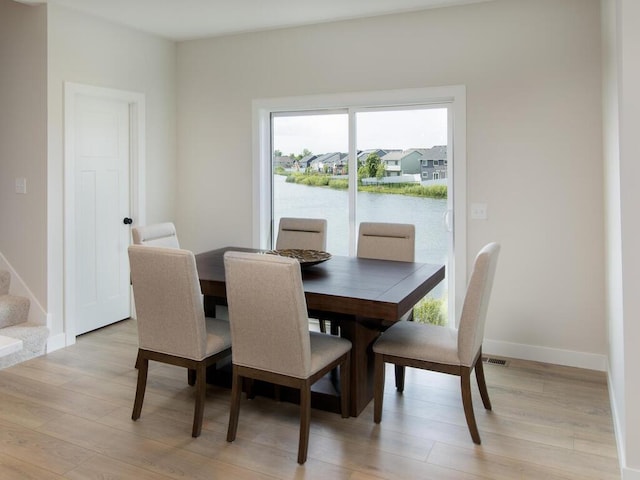 dining room with baseboards, stairs, and light wood-style floors