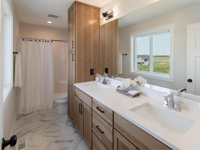 full bathroom with toilet, marble finish floor, a sink, and double vanity