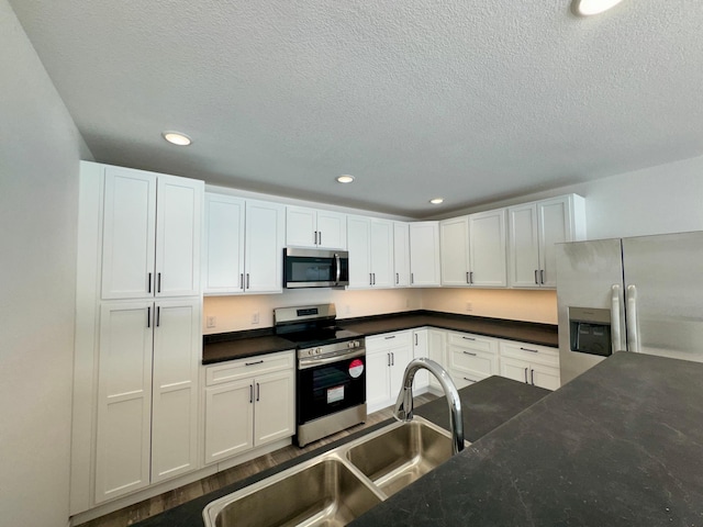 kitchen featuring white cabinets, a textured ceiling, appliances with stainless steel finishes, and sink