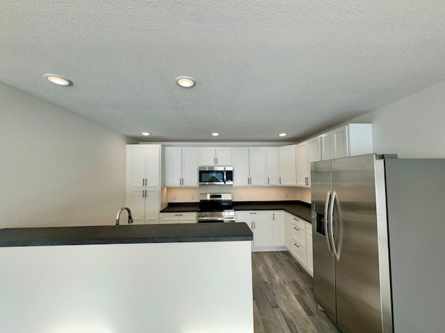 kitchen with sink, stainless steel appliances, a textured ceiling, white cabinets, and dark hardwood / wood-style flooring