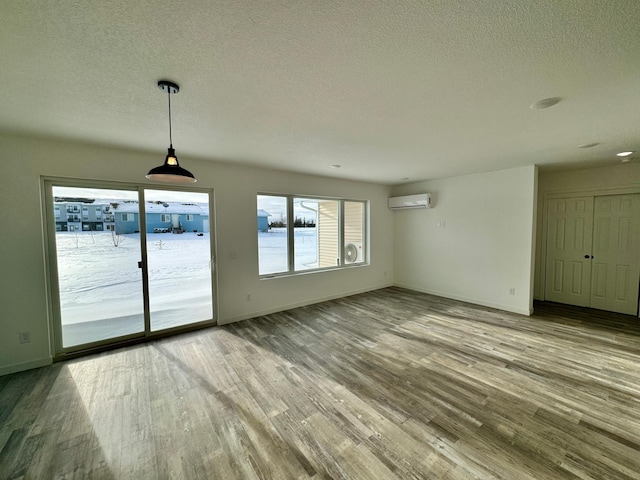 interior space with a textured ceiling, a wall mounted AC, and hardwood / wood-style floors