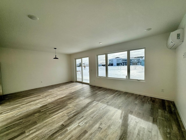 spare room with wood-type flooring and a wall mounted air conditioner