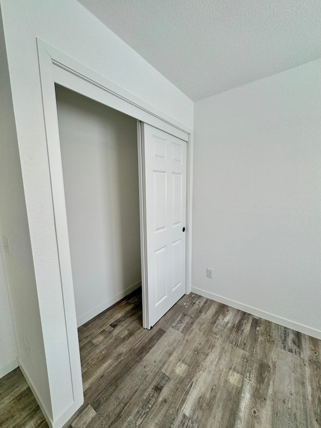 unfurnished bedroom featuring wood-type flooring, a closet, and a textured ceiling