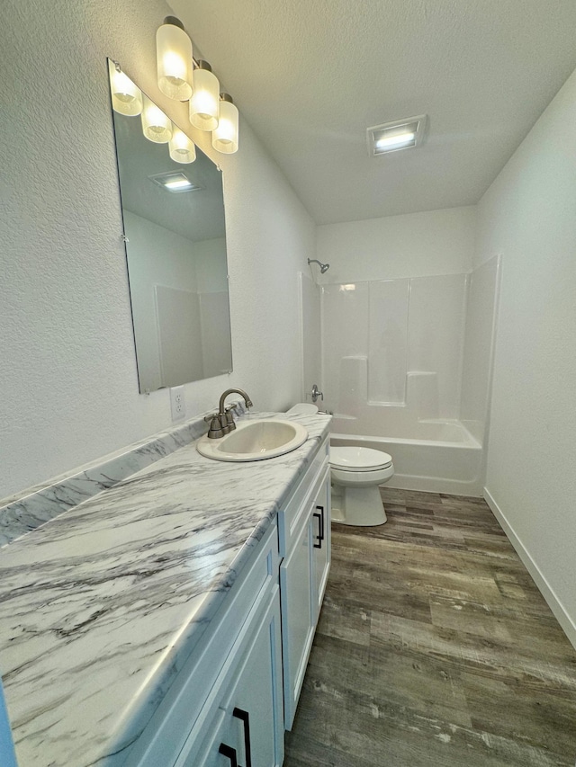 full bathroom featuring toilet, vanity, hardwood / wood-style flooring, shower / tub combination, and a textured ceiling