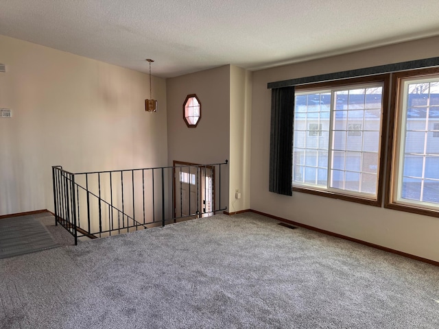 carpeted spare room featuring a textured ceiling