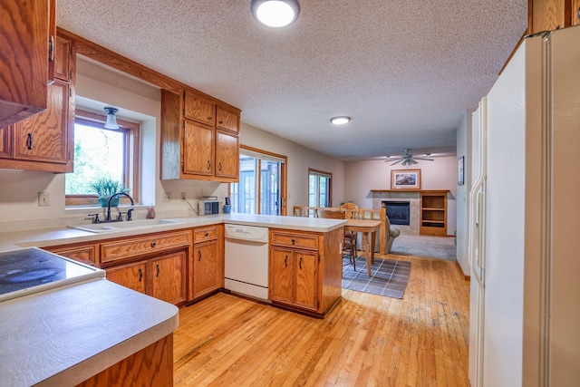 kitchen with sink, dishwasher, kitchen peninsula, and light wood-type flooring