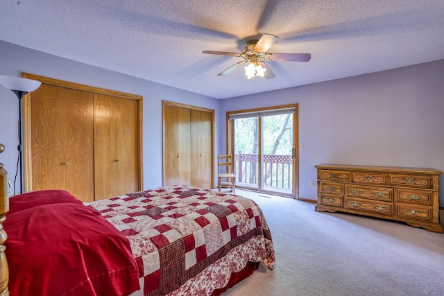 bedroom with carpet flooring, access to outside, a textured ceiling, ceiling fan, and two closets