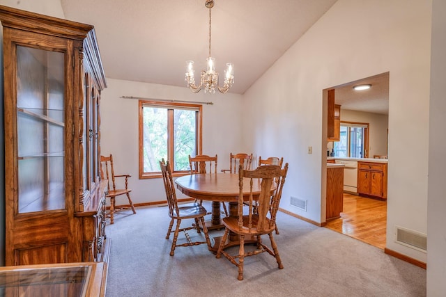 carpeted dining room with a chandelier and vaulted ceiling