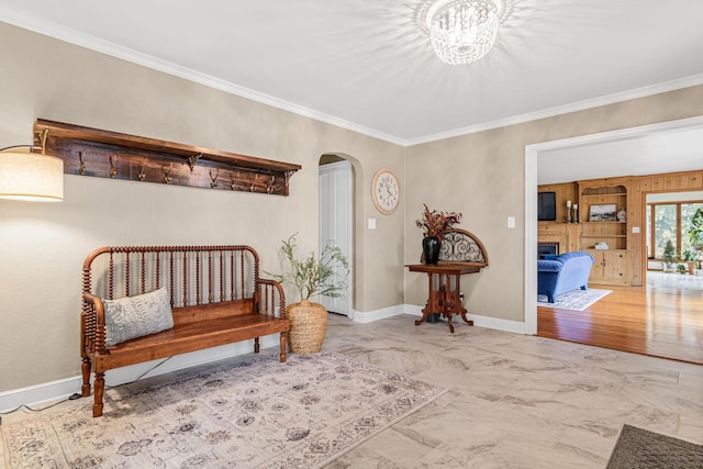 living area featuring ornamental molding, a fireplace, arched walkways, a notable chandelier, and baseboards