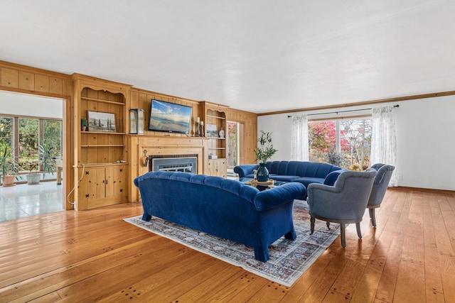 living room with a fireplace, ornamental molding, a healthy amount of sunlight, and light wood-style floors