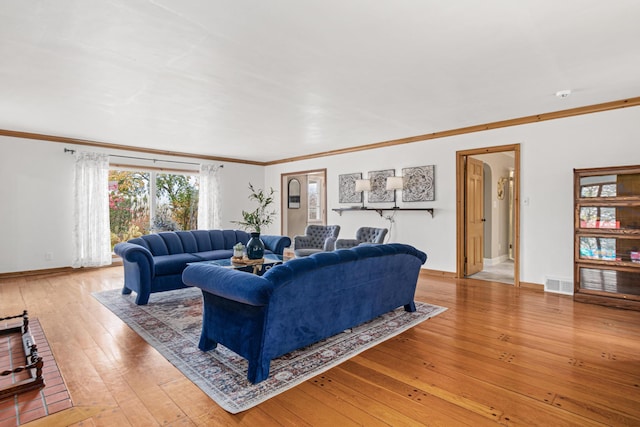 living area with light wood finished floors, crown molding, visible vents, and baseboards