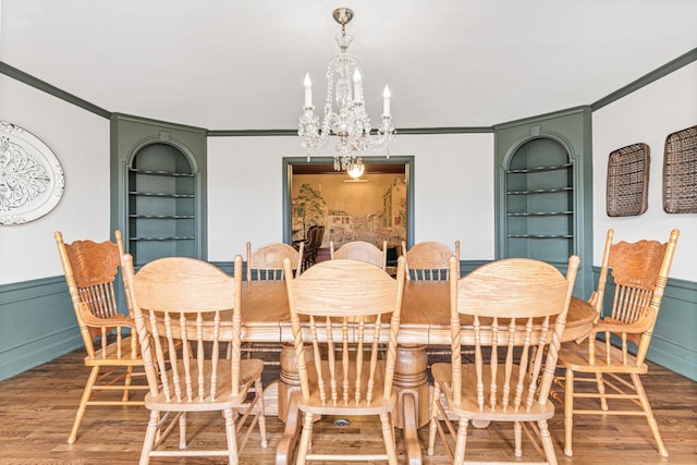 dining area featuring wood finished floors, built in shelves, and ornamental molding