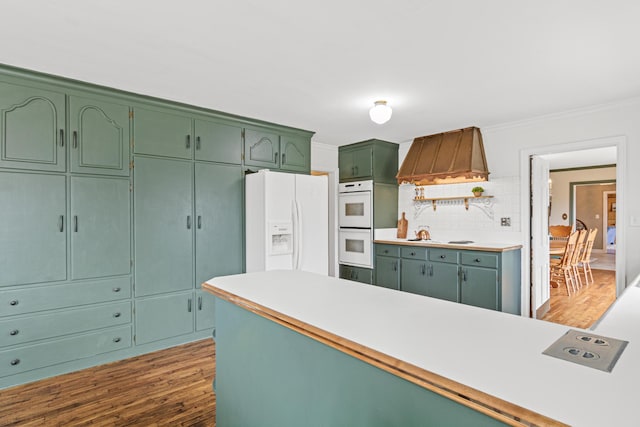 kitchen with green cabinetry, white appliances, tasteful backsplash, and wood finished floors