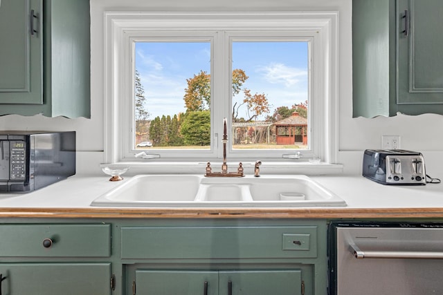 kitchen with green cabinetry, black microwave, a sink, and dishwasher