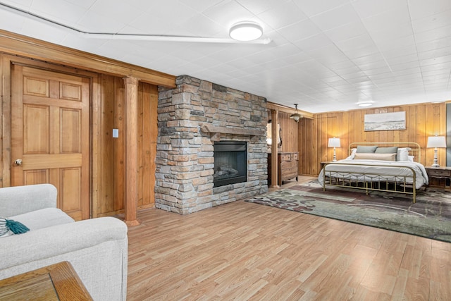 bedroom with wooden walls, wood finished floors, and a fireplace