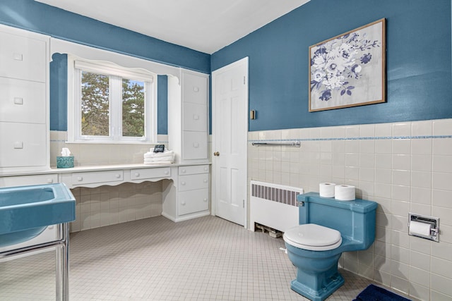 bathroom featuring toilet, tile patterned floors, tile walls, wainscoting, and radiator heating unit