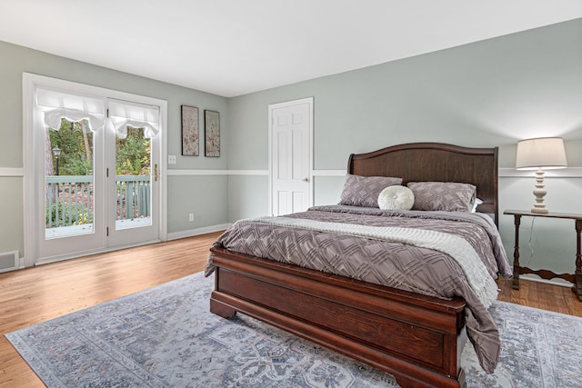 bedroom with access to outside, baseboards, visible vents, and wood finished floors