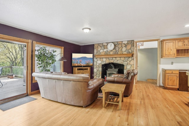 living room featuring a textured ceiling, light hardwood / wood-style floors, a wood stove, and ornamental molding