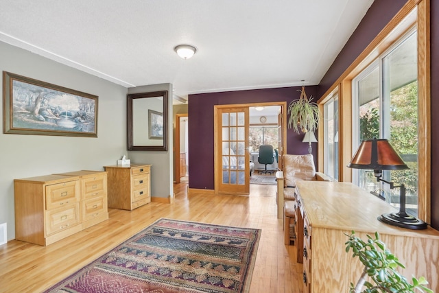 interior space with a wealth of natural light, light hardwood / wood-style flooring, french doors, and ornamental molding