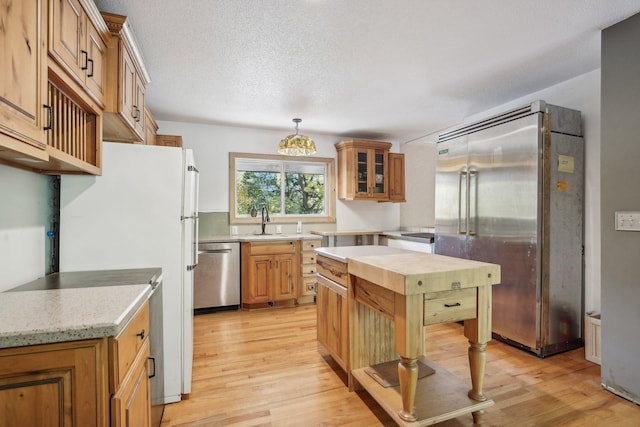 kitchen featuring a textured ceiling, appliances with stainless steel finishes, and light hardwood / wood-style flooring