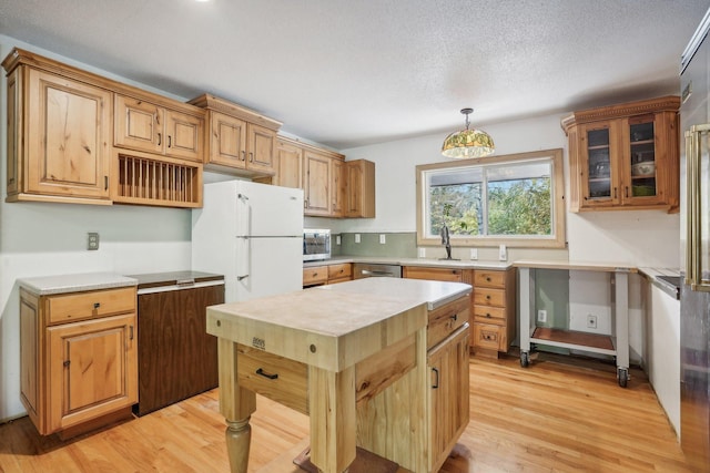 kitchen featuring sink, light hardwood / wood-style floors, a textured ceiling, decorative light fixtures, and appliances with stainless steel finishes