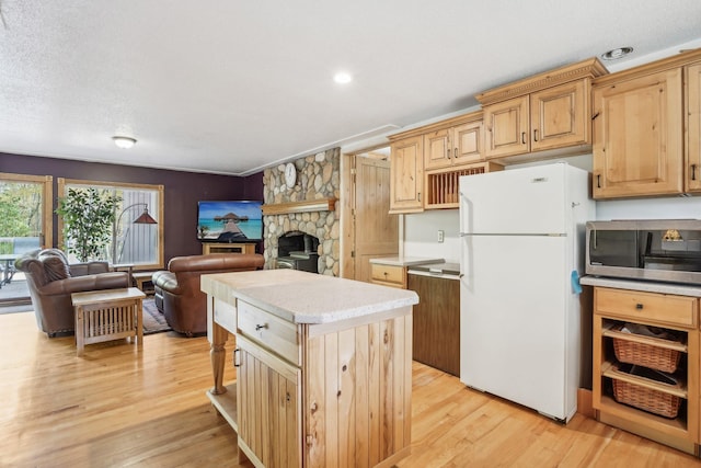 kitchen with a center island, light hardwood / wood-style floors, a fireplace, light brown cabinetry, and white fridge