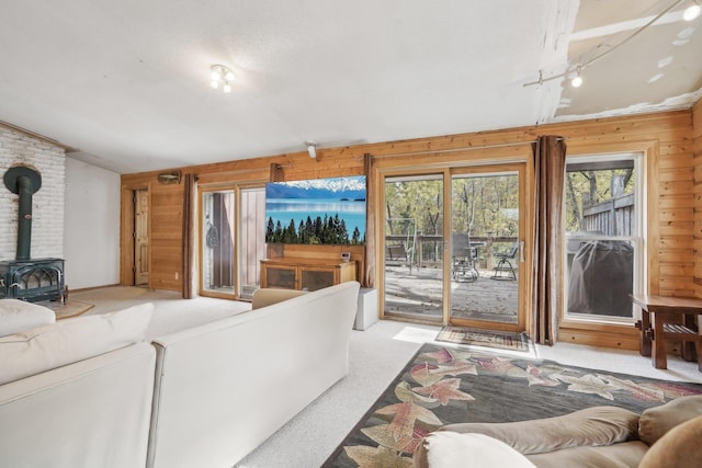 carpeted living room with a wood stove, wooden walls, and vaulted ceiling