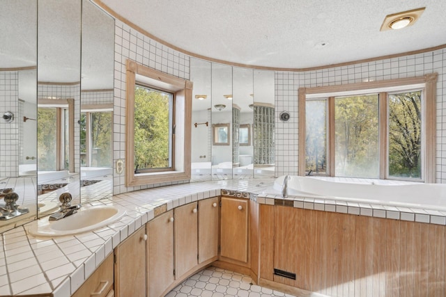 bathroom with vanity, tile patterned flooring, ornamental molding, a textured ceiling, and tile walls