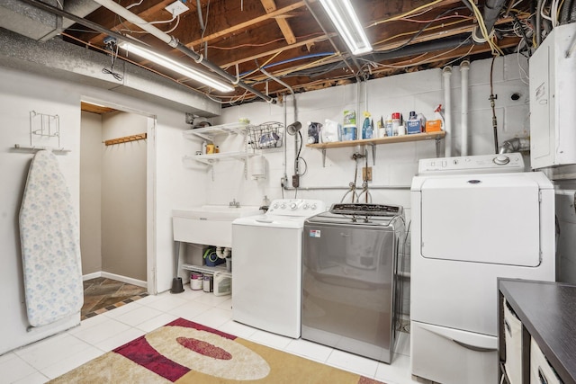 clothes washing area with washing machine and dryer, electric panel, light tile patterned flooring, and sink